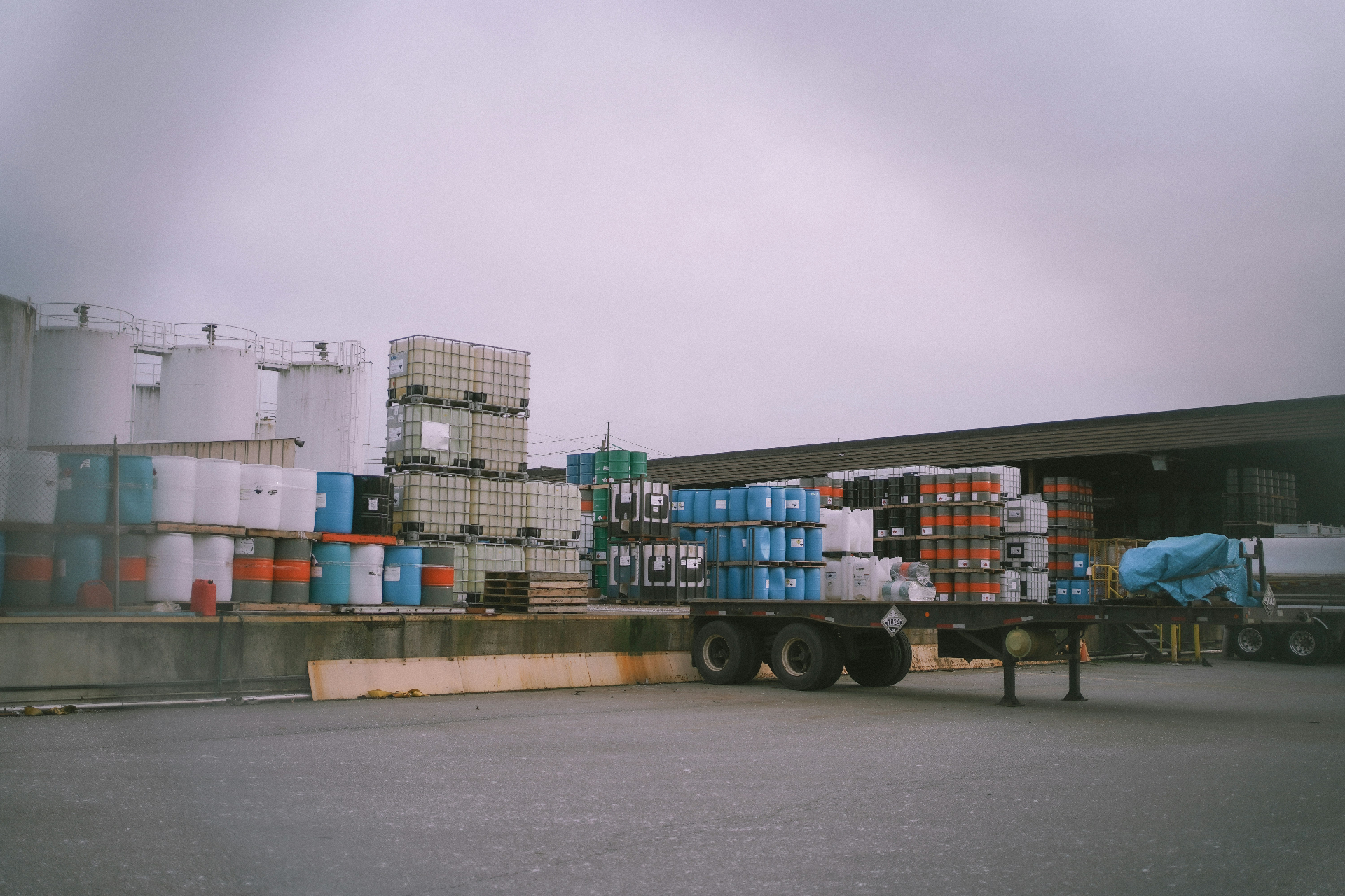 Chemical drums and totes staged in a supply warehouse yard